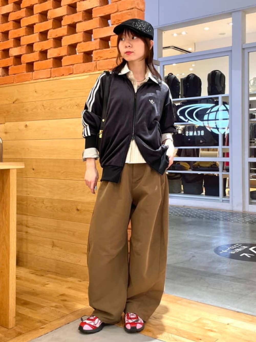 ブラック系のハンドバッグ、ブラウン系のチノパンツ、ベージュ系のシャツ/ブラウスを着用したレディースの秋コーディネートの1枚目の写真