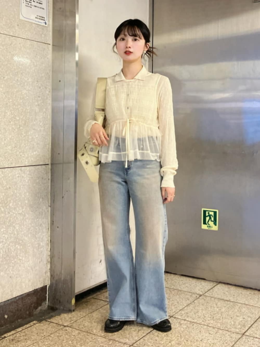 ブルー系のデニムパンツ、ベージュ系のトートバッグ、ホワイト系のTシャツ/カットソーを着用したレディースの春コーディネートの1枚目の写真