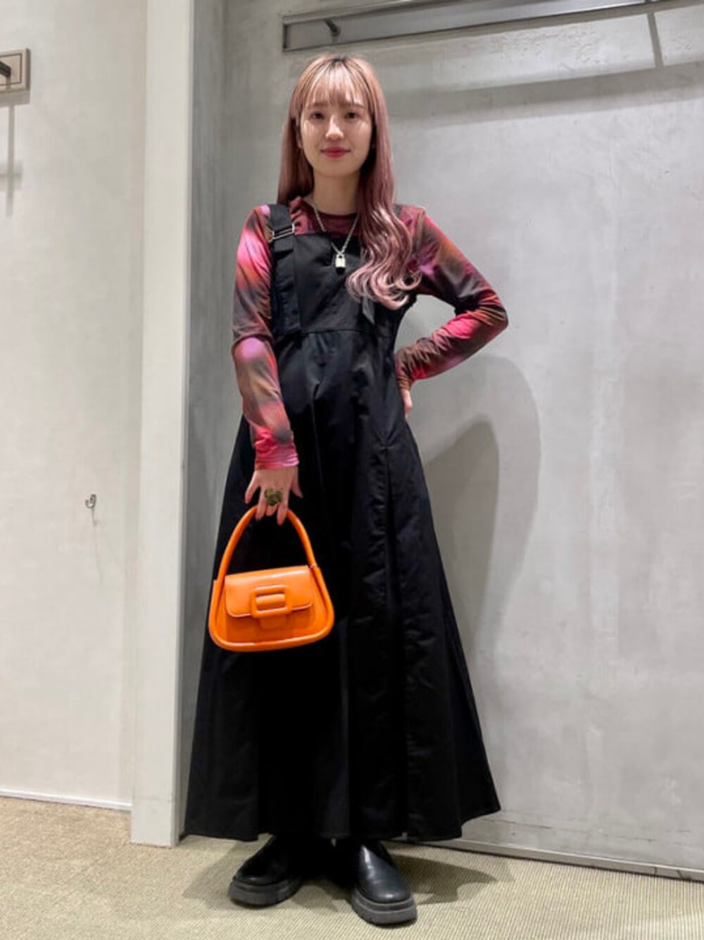 オレンジ系のショルダーバッグ、レッド系のTシャツ/カットソー、ブラック系のワンピースを着用したレディースの春コーディネートの1枚目の写真