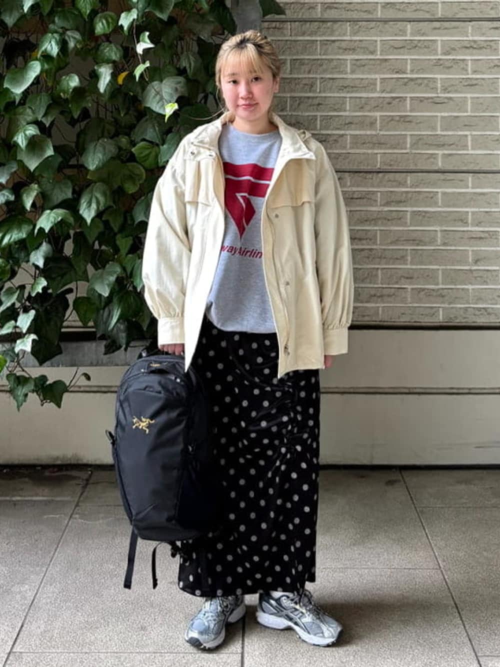 ブラック系のスカート、グレー系のスウェット、ホワイト系のマウンテンパーカーを着用したレディースの春コーディネートの1枚目の写真