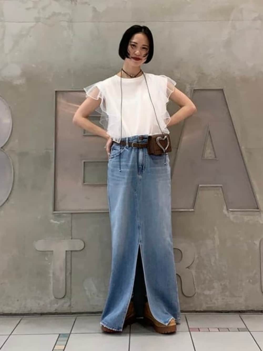 ブルー系のスカート、ホワイト系のTシャツ/カットソー、ブラウン系のブーツを着用したレディースの春コーディネートの1枚目の写真