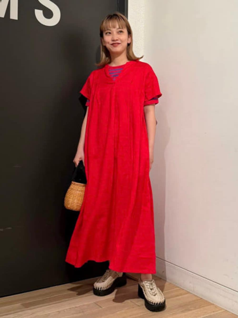 レッド系のワンピース、ブラウン系のかごバッグ、ベージュ系のサンダルを着用したレディースの春コーディネートの1枚目の写真