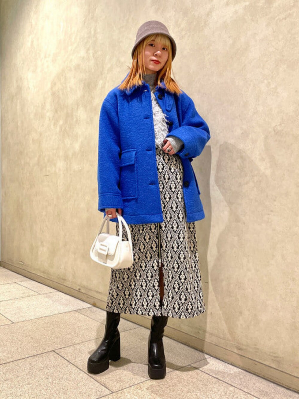 ホワイト系のショルダーバッグ、グレー系のニット/セーター、ブルー系のその他アウターを着用したレディースの冬コーディネートの1枚目の写真