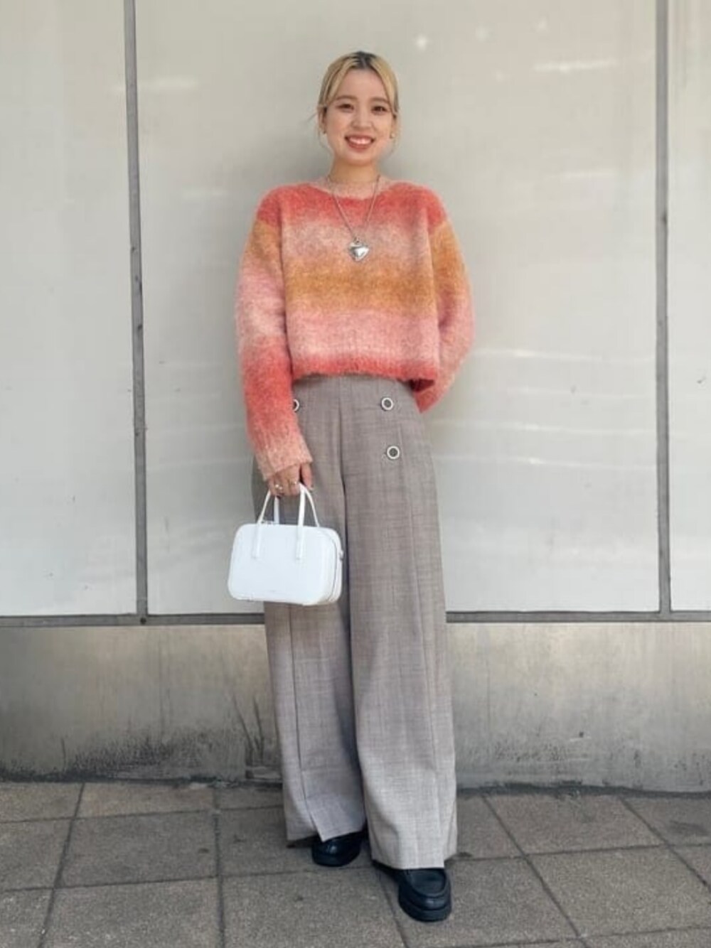 シルバー系のその他パンツ、オレンジ系のニット/セーター、ホワイト系のショルダーバッグを着用したレディースの秋コーディネートの1枚目の写真