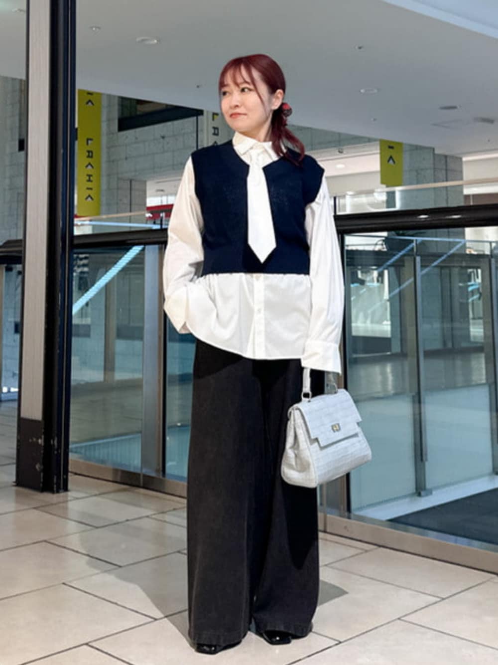 ブルー系のハンドバッグ、ブラウン系のスウェットパンツ、ブルー系のベストを着用したレディースの秋コーディネートの1枚目の写真