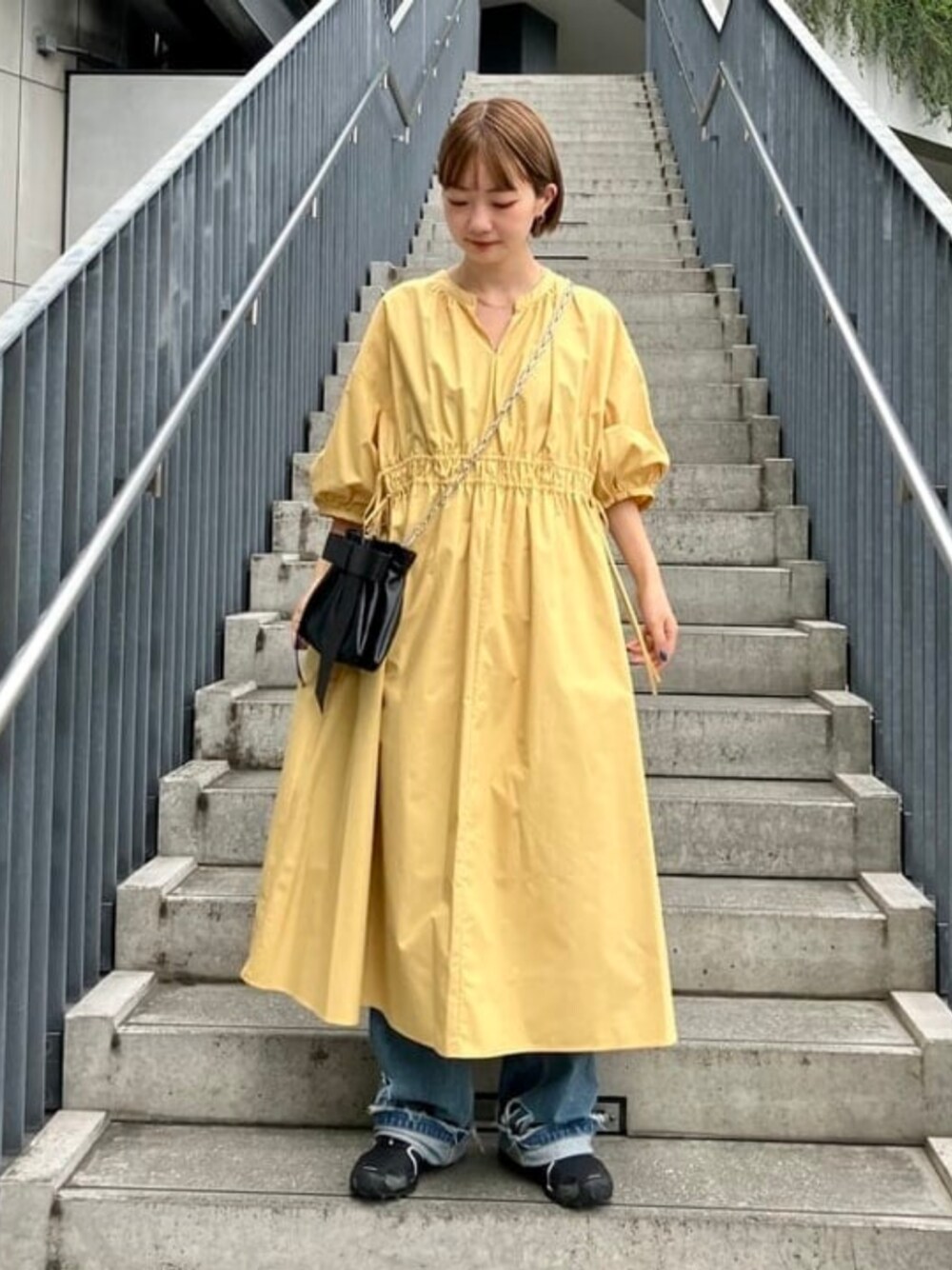 ブラック系のショルダーバッグ、イエロー系のワンピースを着用したレディースの夏コーディネートの1枚目の写真