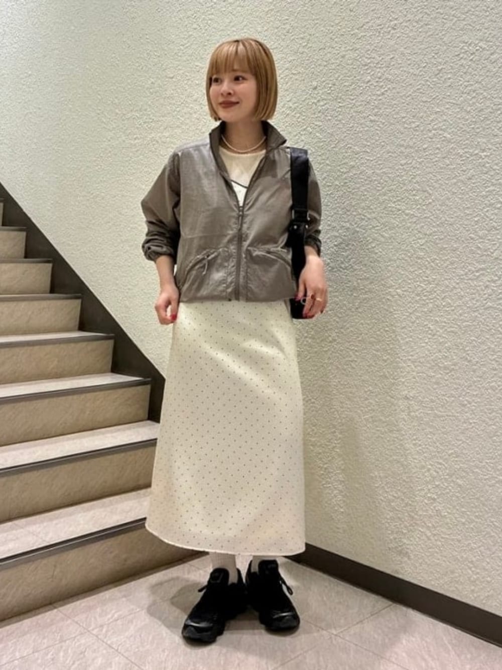 ホワイト系のワンピース、ブラック系のスニーカーを着用したレディースの春コーディネートの1枚目の写真