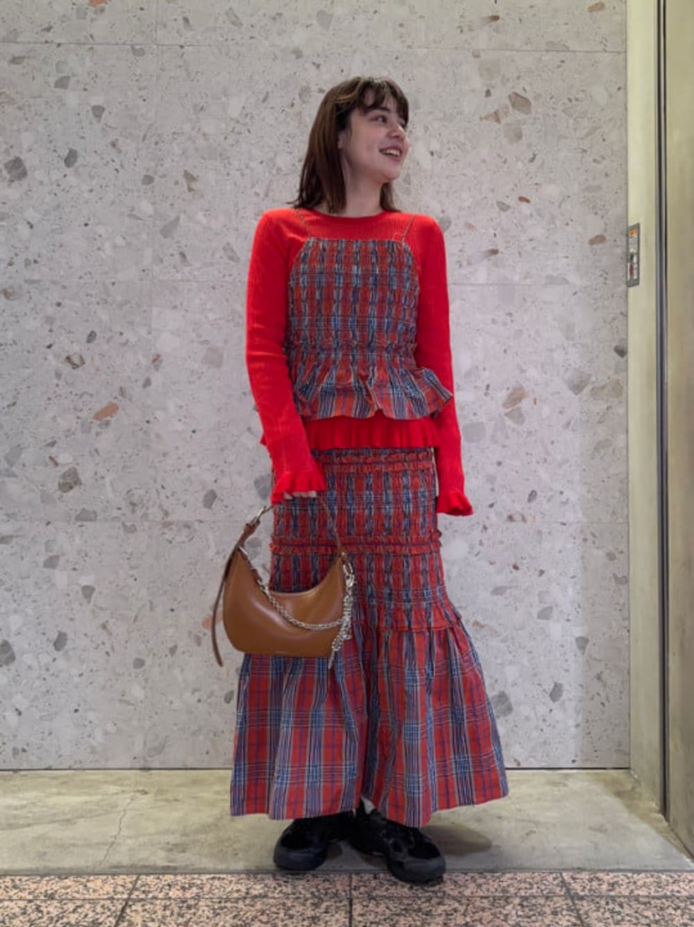 ブラウン系のトートバッグ、レッド系のニット/セーター、レッド系のスカートを着用したレディースの春コーディネートの1枚目の写真