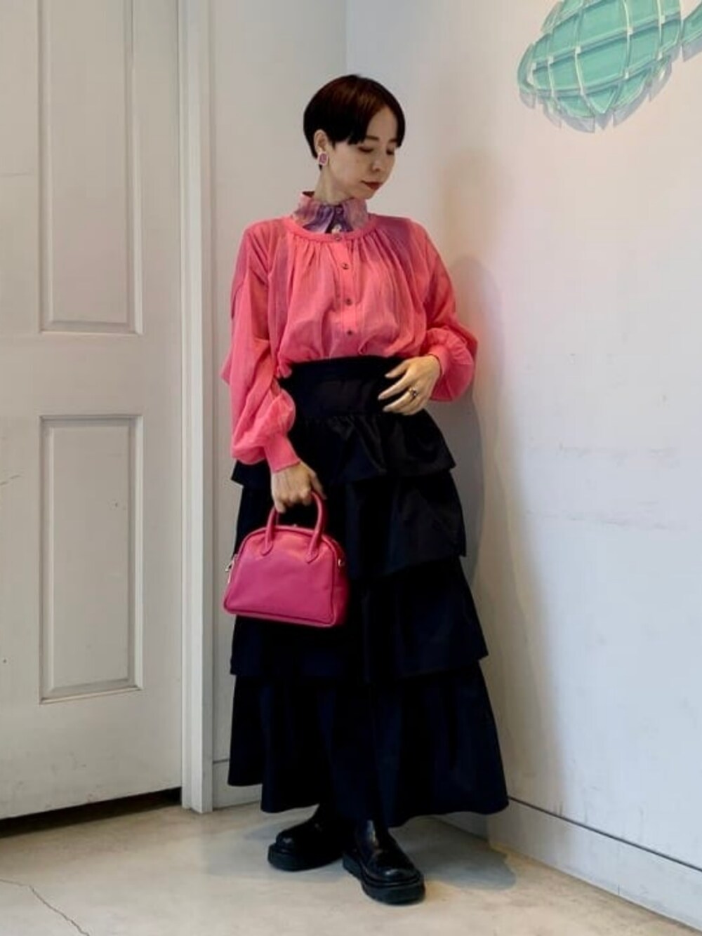 レッド系のカーディガン/ボレロ、ブラック系のスカート、レッド系のトートバッグを着用したレディースの冬コーディネートの1枚目の写真