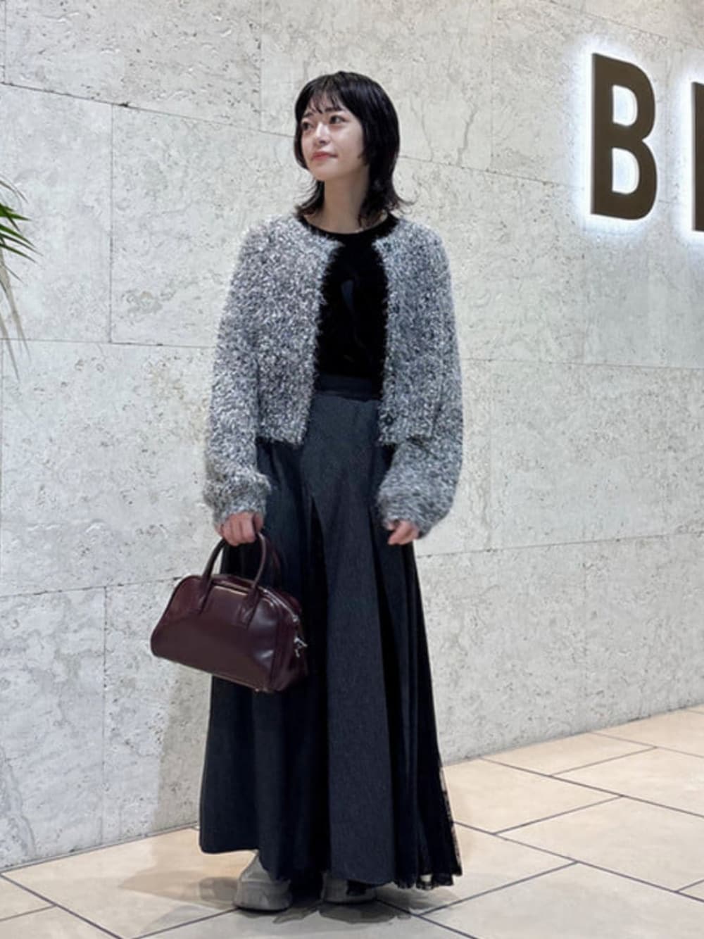 ブラウン系のボストンバッグ、シルバー系のカーディガン/ボレロ、ブラック系のTシャツ/カットソーを着用したレディースの秋コーディネートの1枚目の写真