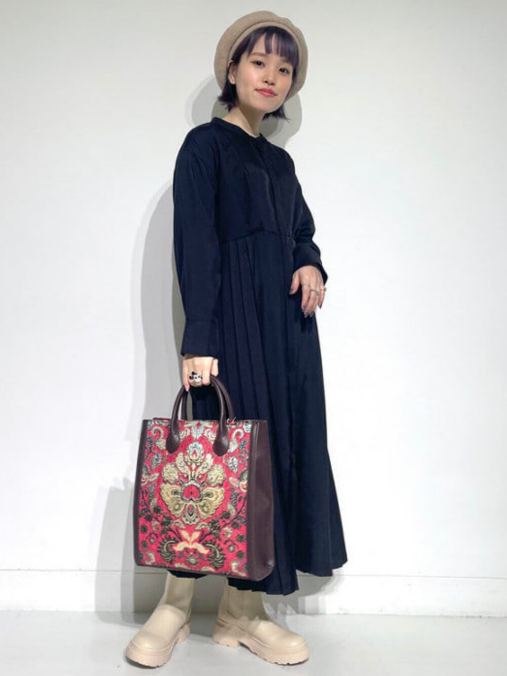 ブラウン系のトートバッグ、ブラック系のワンピース、ベージュ系のブーツを着用したレディースの秋コーディネートの1枚目の写真