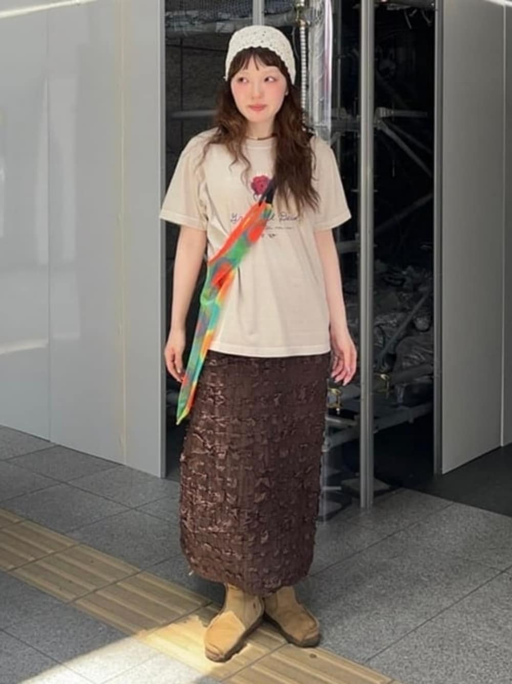 ブラウン系のスカート、ベージュ系のTシャツ/カットソー、ホワイト系のニットキャップ/ビーニーを着用したレディースの夏コーディネートの1枚目の写真