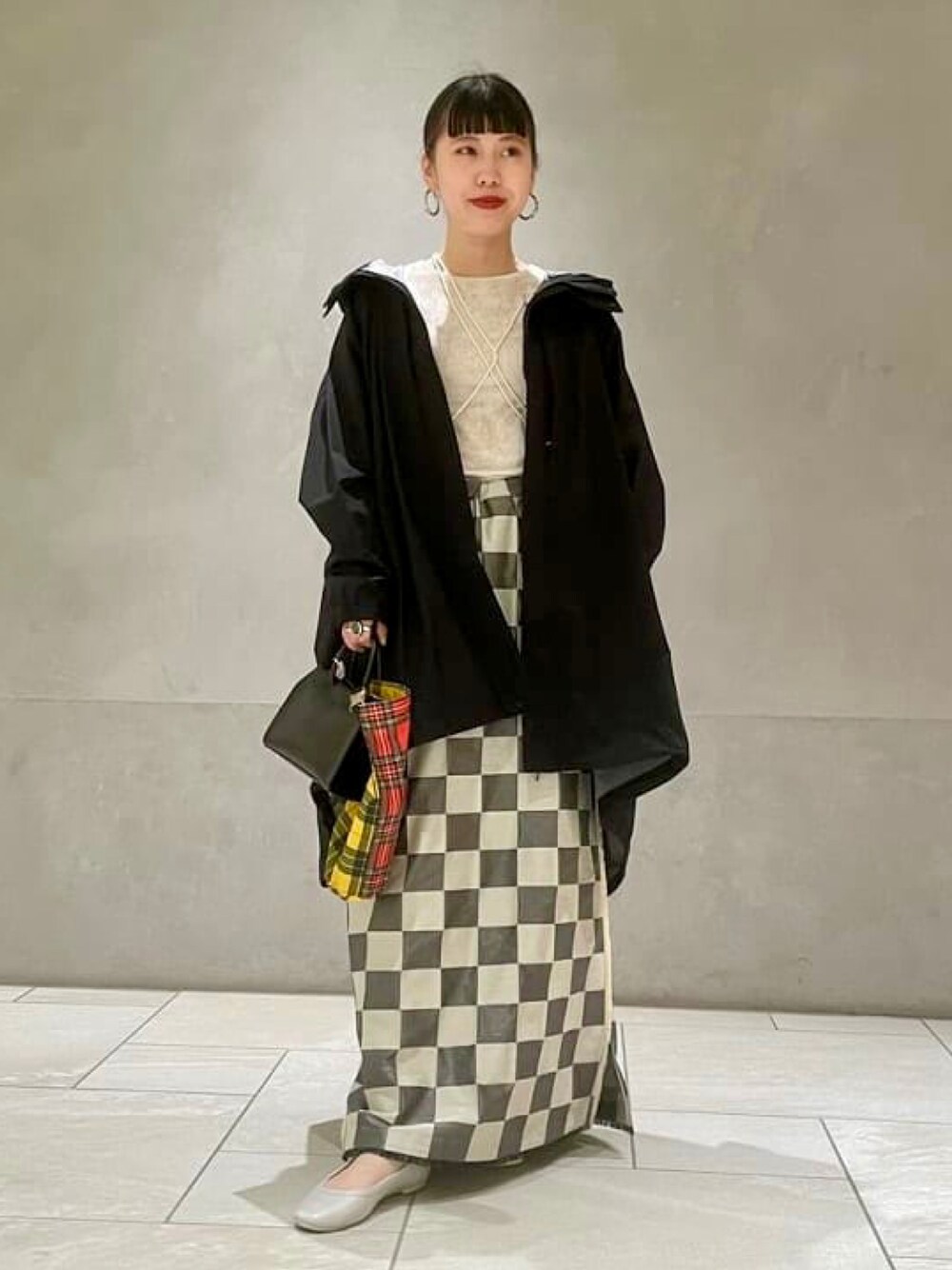 ブラック系のポンチョ、ベージュ系のレインシューズ、ブラック系のショルダーバッグを着用したレディースの夏コーディネートの1枚目の写真