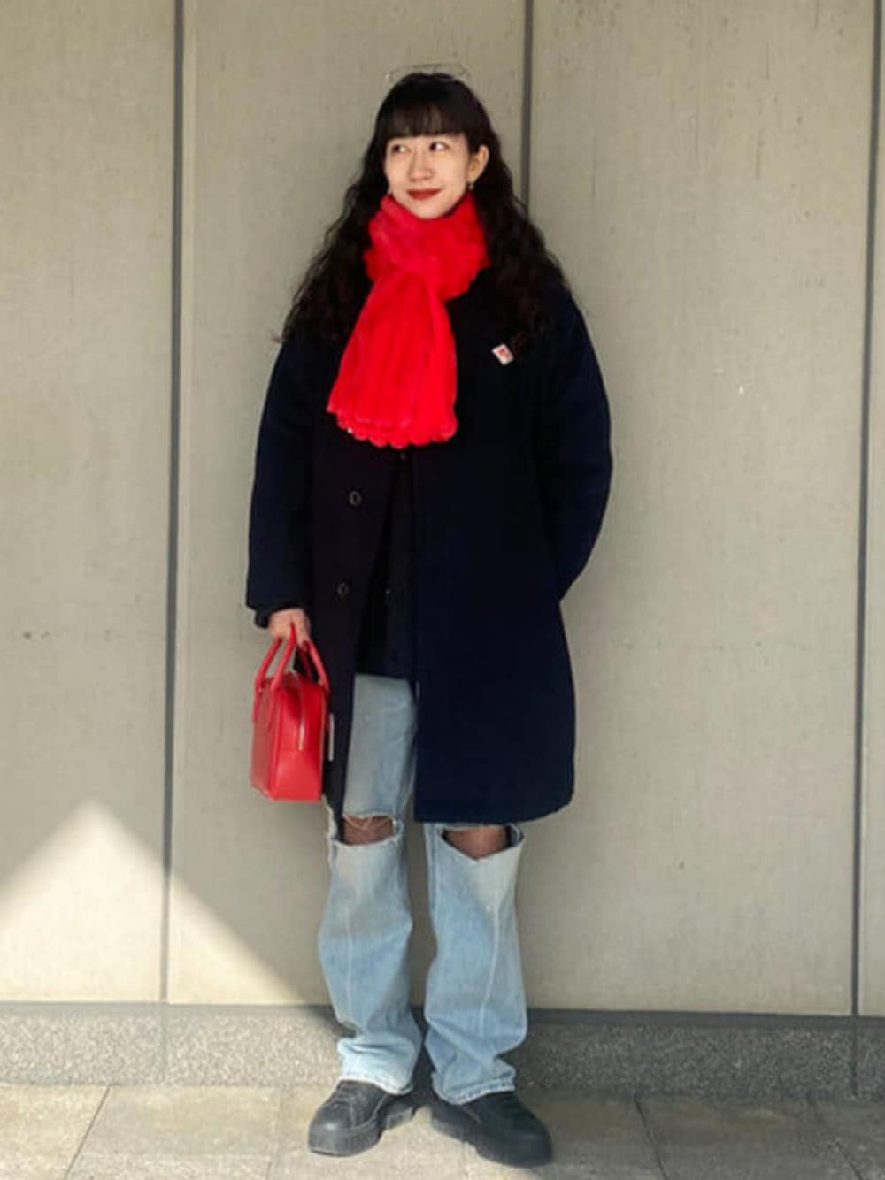 レッド系のボストンバッグ、ブルー系のダウンジャケット/コート、レッド系のマフラーを着用したレディースの冬コーディネートの1枚目の写真