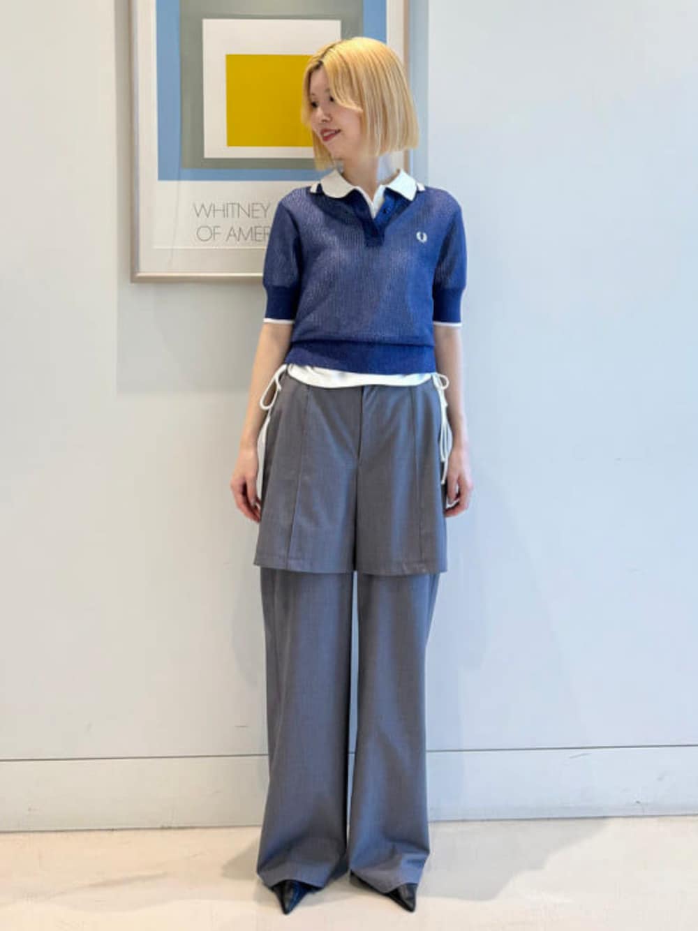 ブルー系のポロシャツ、シルバー系のスラックスを着用したレディースの冬コーディネートの1枚目の写真