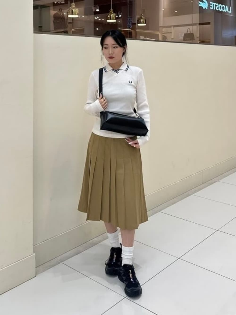 ブラック系のトートバッグ、グリーン系のスカート、ピンク系のポロシャツを着用したレディースの秋コーディネートの1枚目の写真