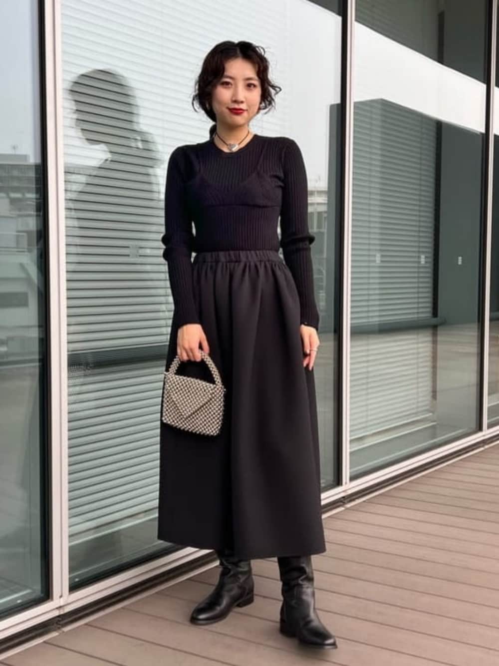 シルバー系のメッセンジャーバッグ、ブラック系のニット/セーター、ブラック系のブーツを着用したレディースの冬コーディネートの1枚目の写真