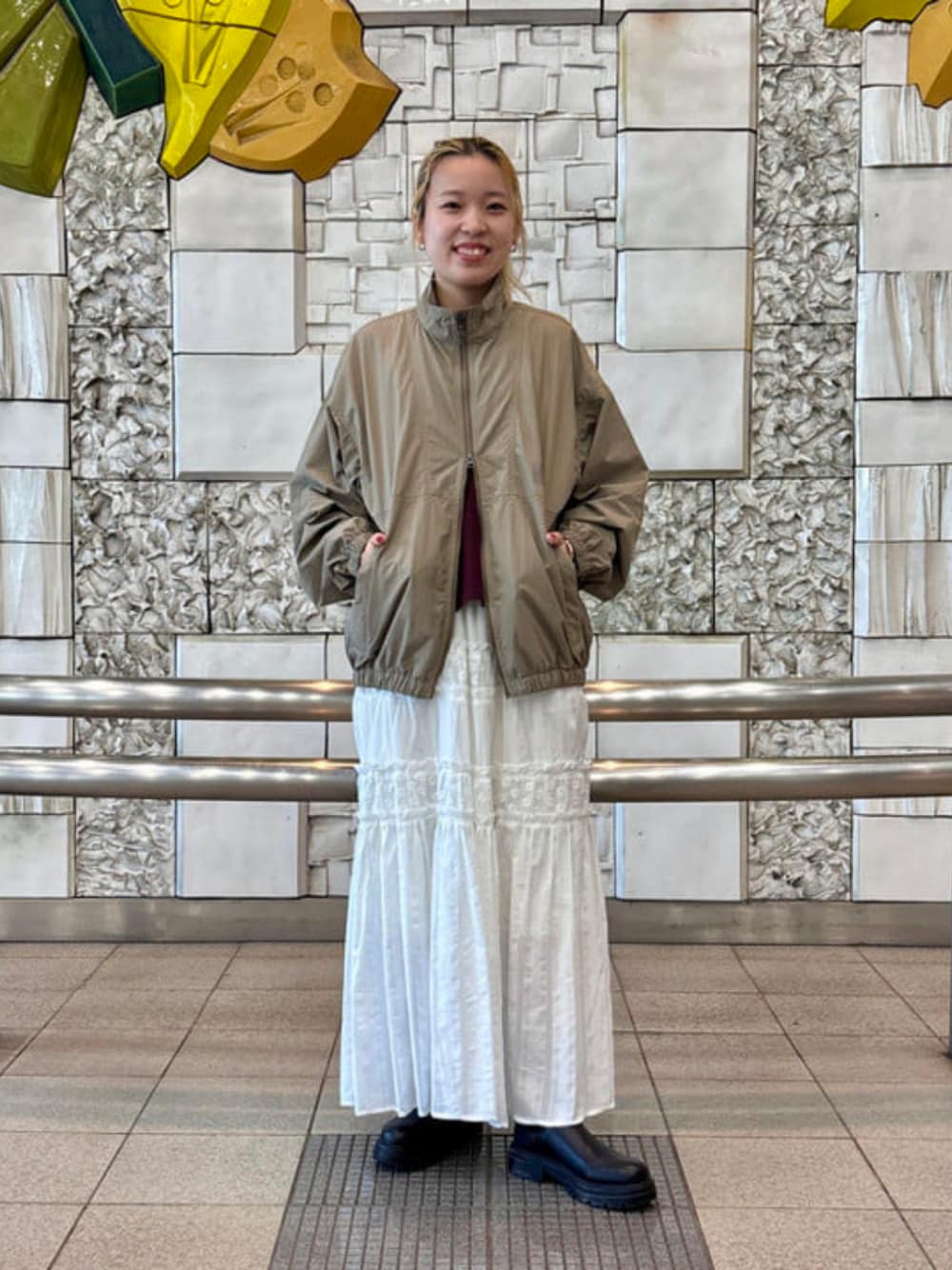 ホワイト系のスカート、ベージュ系のナイロンジャケットを着用したレディースの秋コーディネートの1枚目の写真