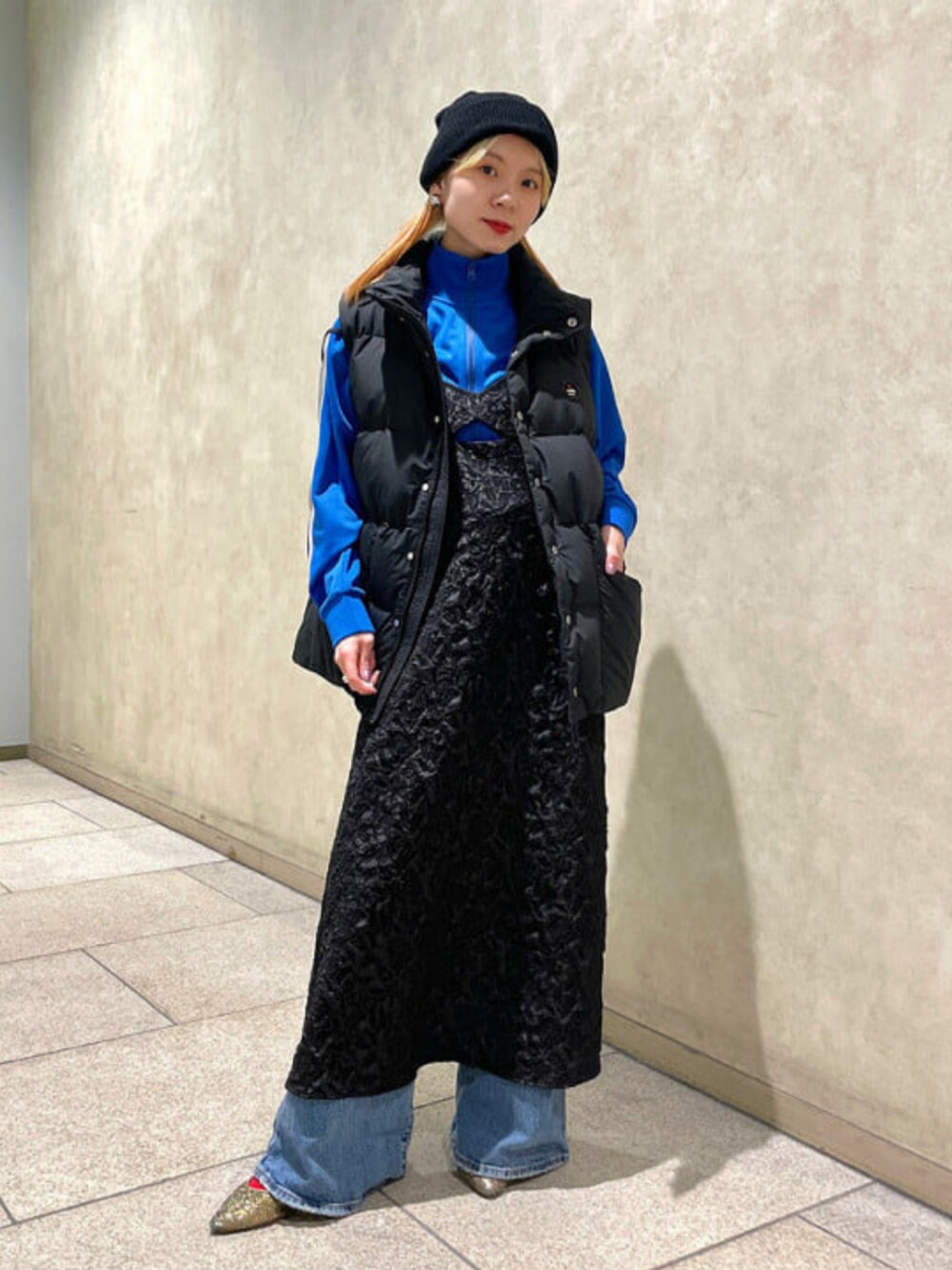 ブラック系のワンピース、ブルー系のジャージ、ブラック系のニットキャップ/ビーニーを着用したレディースの冬コーディネートの1枚目の写真