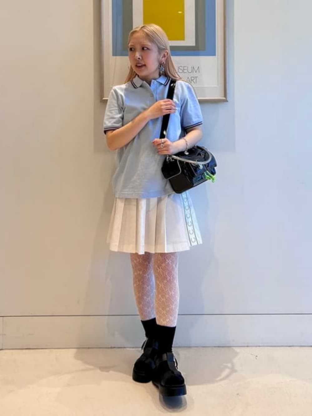 ブルー系のポロシャツ、ブラック系のサンダル、ブラック系のショルダーバッグを着用したレディースの冬コーディネートの1枚目の写真