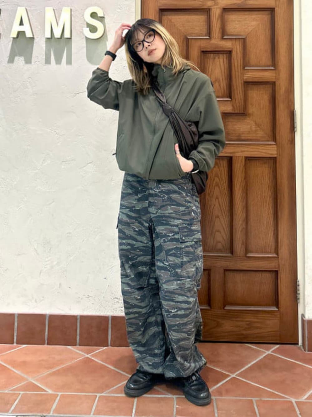 グリーン系のナイロンジャケット、グレー系のカーゴパンツ、シルバー系のリングを着用したレディースの春コーディネートの1枚目の写真