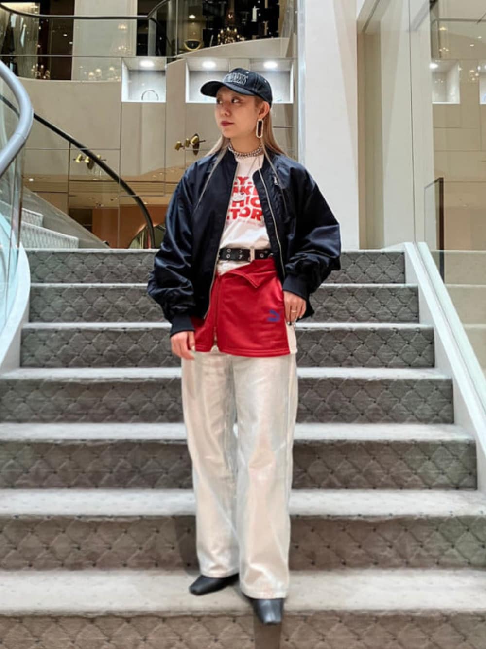 レッド系のスカート、ブラック系のMA-1、ホワイト系のデニムパンツを着用したレディースの冬コーディネートの1枚目の写真