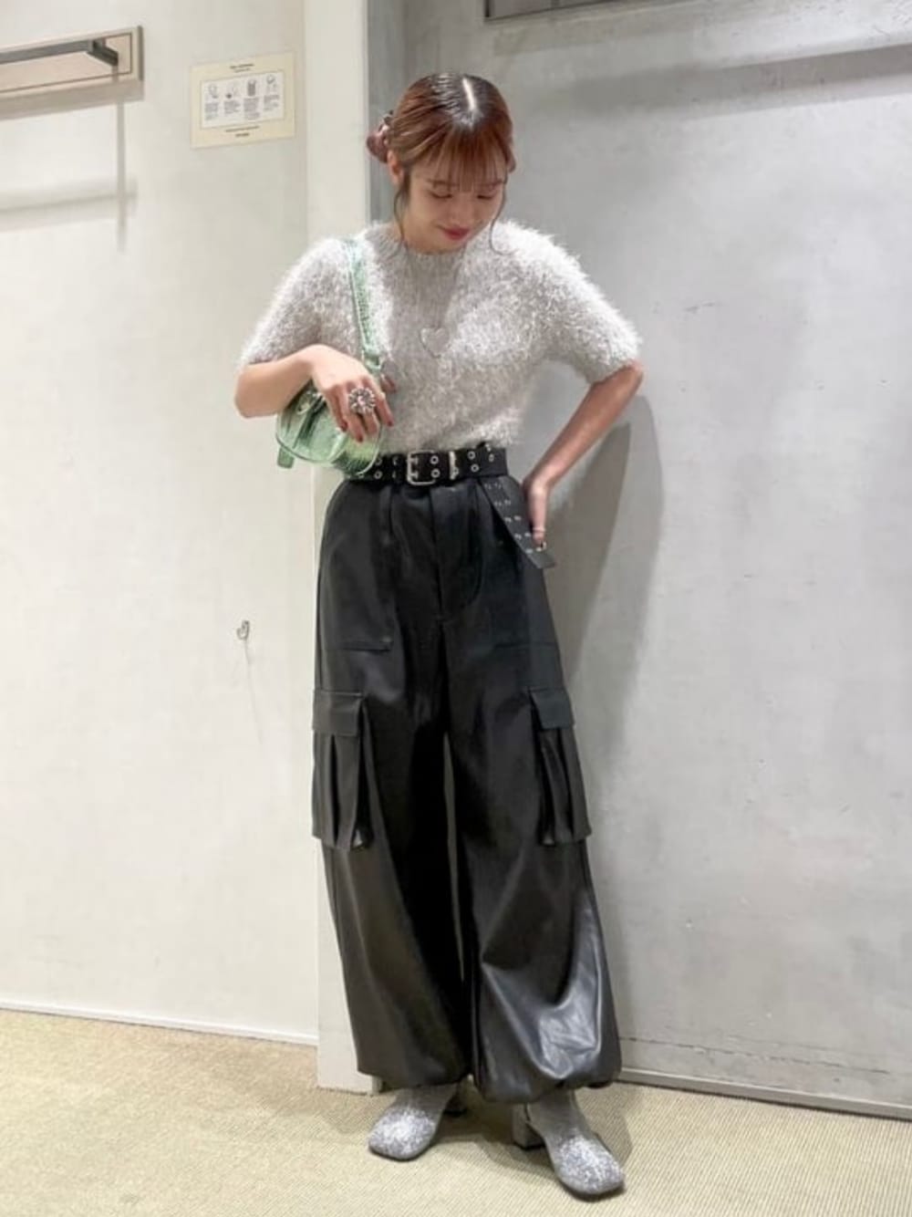 グリーン系のハンドバッグ、シルバー系のニット/セーター、シルバー系のブーツを着用したレディースの秋コーディネートの1枚目の写真