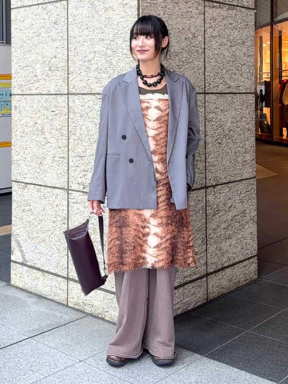 ブラウン系のスカート、ブラウン系のトートバッグ、グレー系のテーラードジャケットを着用したレディースの冬コーディネートの1枚目の写真