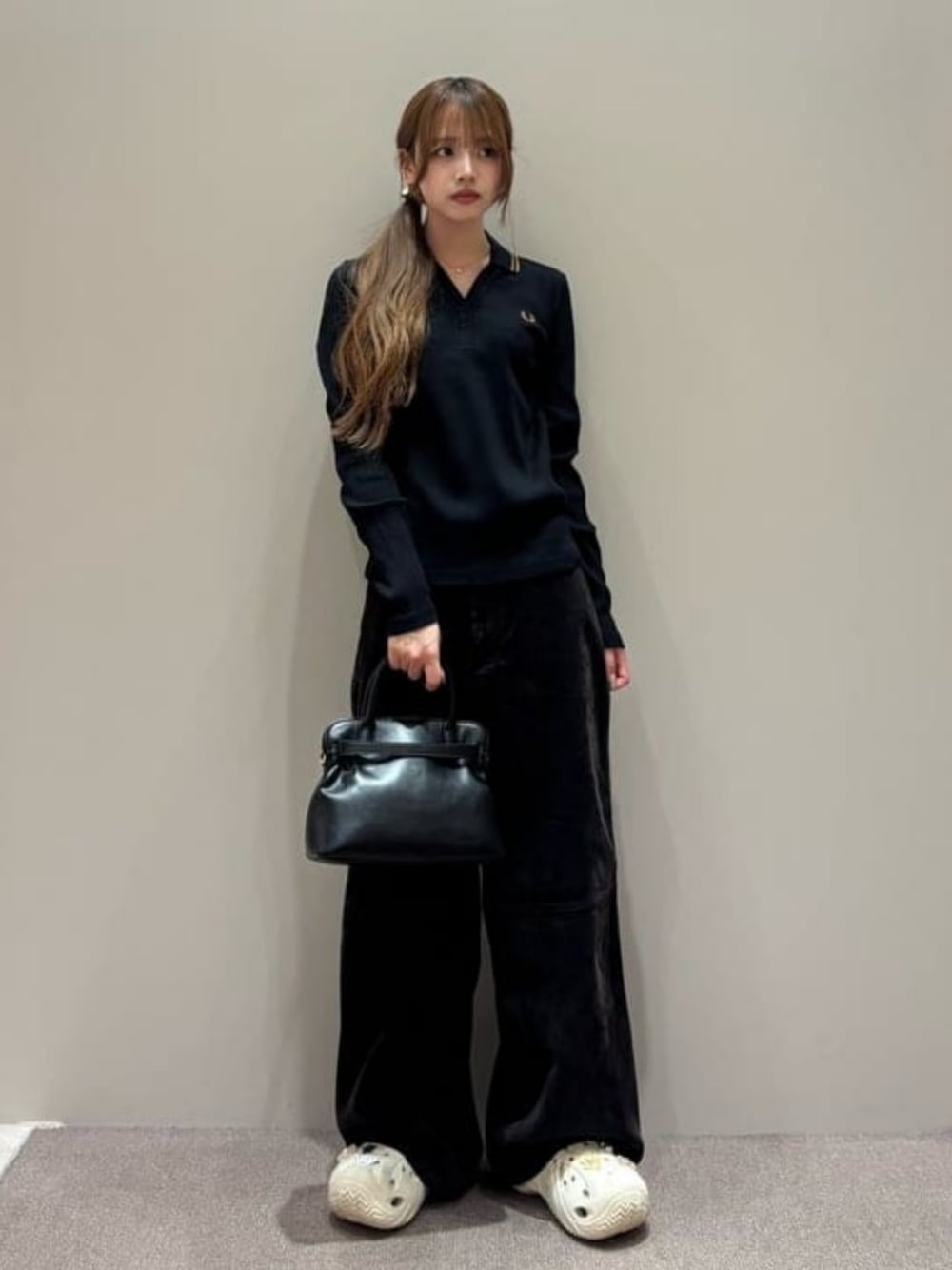 ブラウン系のデニムパンツ、ブラック系のポロシャツ、ブラック系のトートバッグを着用したレディースの秋コーディネートの1枚目の写真