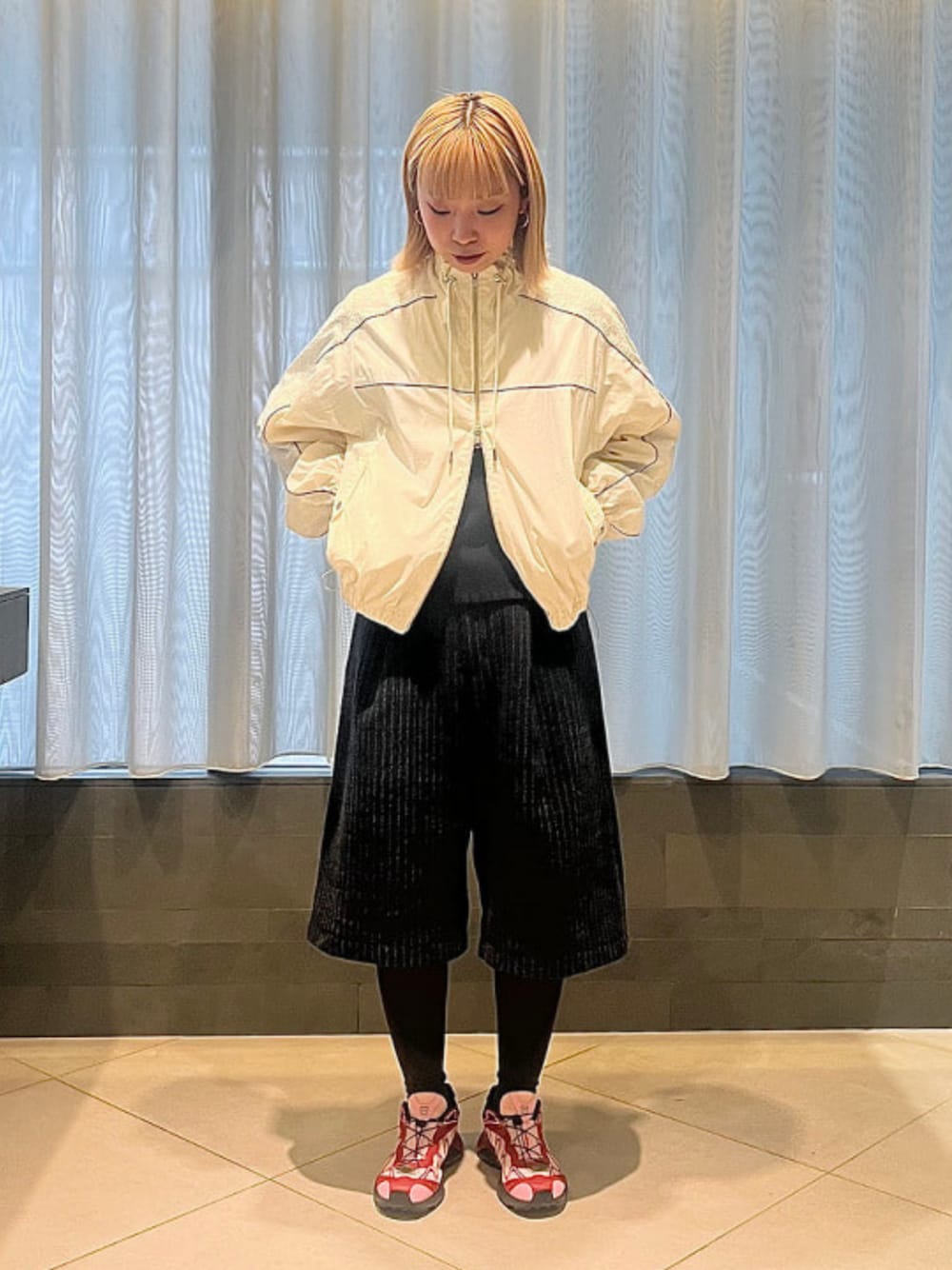 ピンク系のスニーカー、グレー系のその他パンツ、ホワイト系のブルゾンを着用したレディースの秋コーディネートの1枚目の写真