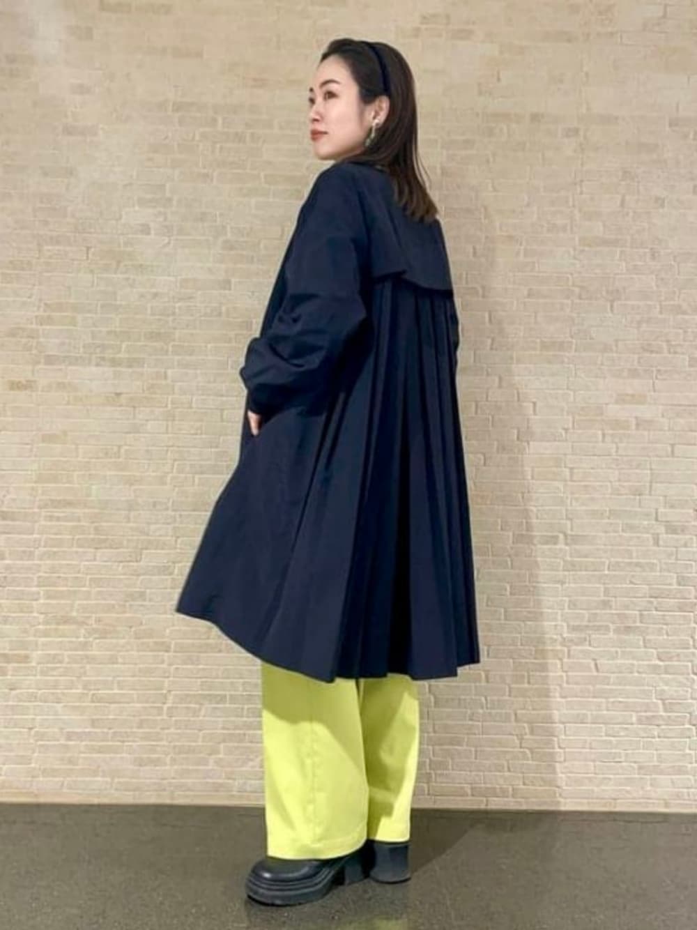 ブラック系のノーカラーコート、グリーン系のその他パンツを着用したレディースの春コーディネートの1枚目の写真