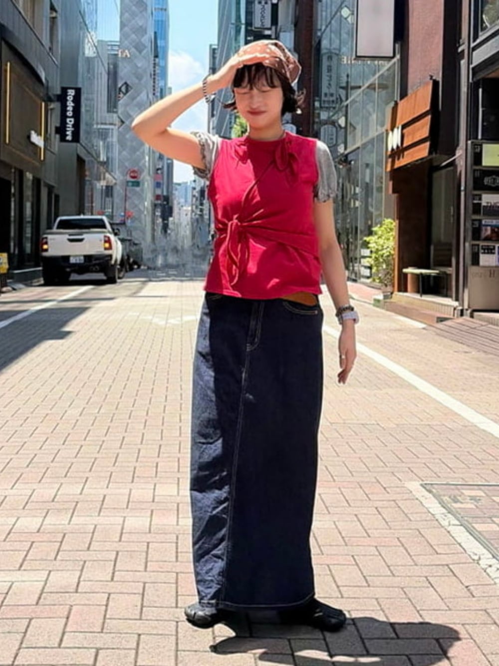 レッド系のTシャツ/カットソー、ブルー系のスカート、ブラウン系のハンカチ/ハンドタオルを着用したレディースの夏コーディネートの1枚目の写真