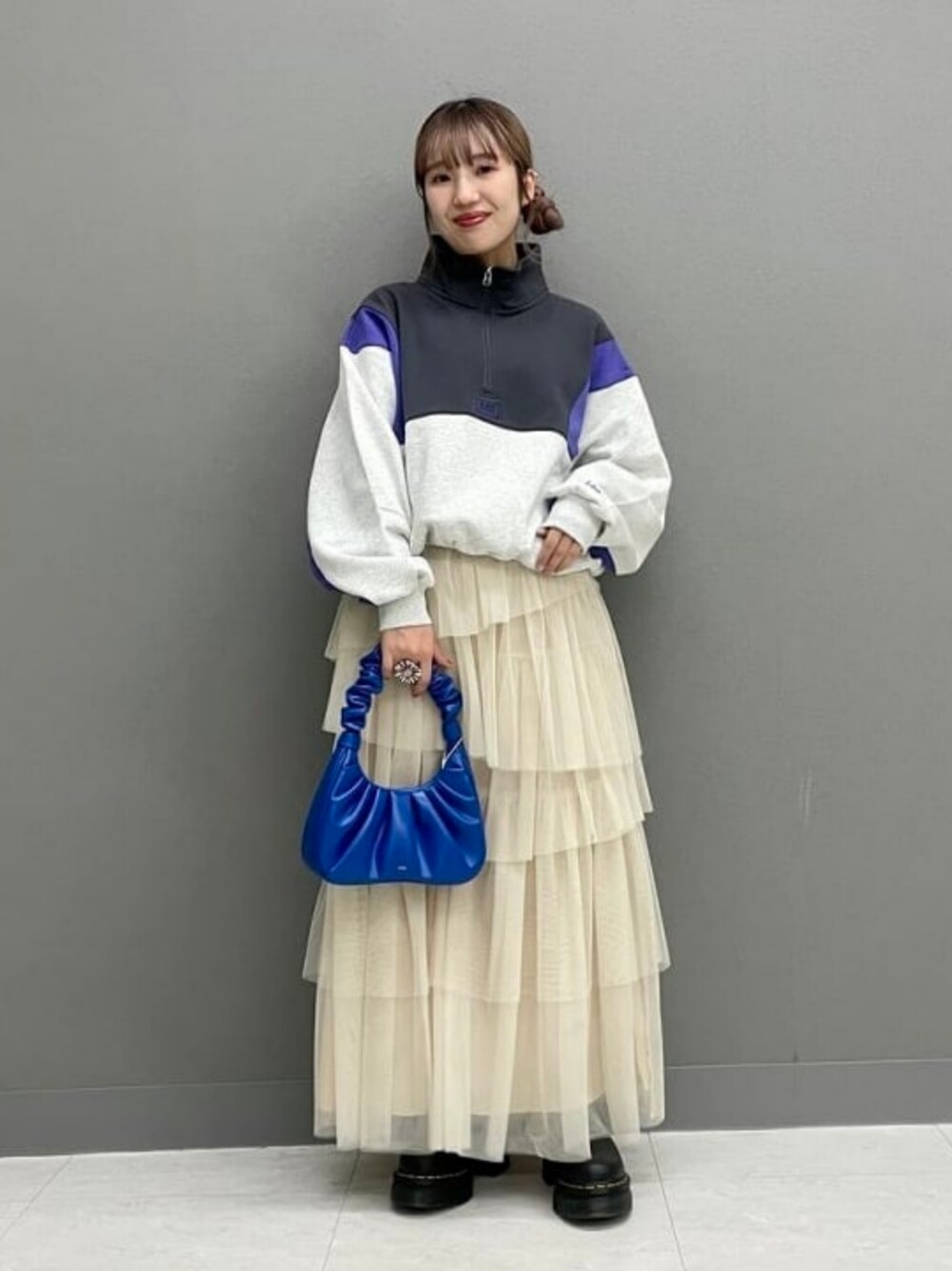 ブルー系のメッセンジャーバッグ、ブラック系のブーツ、ホワイト系のスカートを着用したレディースの秋コーディネートの1枚目の写真