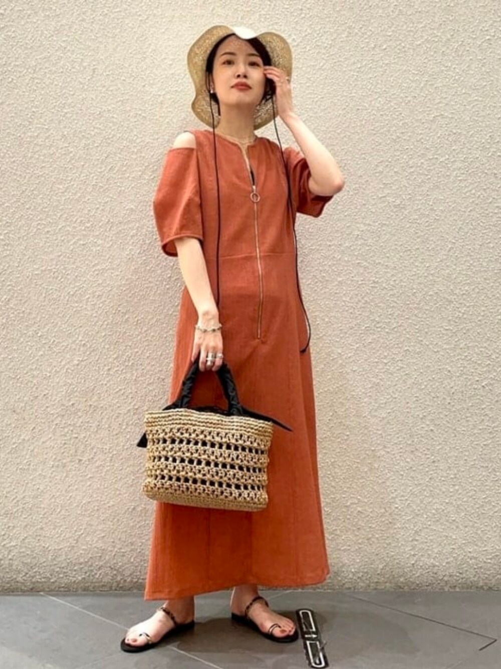 ブラック系のかごバッグ、ブラウン系のワンピース、ゴールド系のサンダルを着用したレディースの夏コーディネートの1枚目の写真