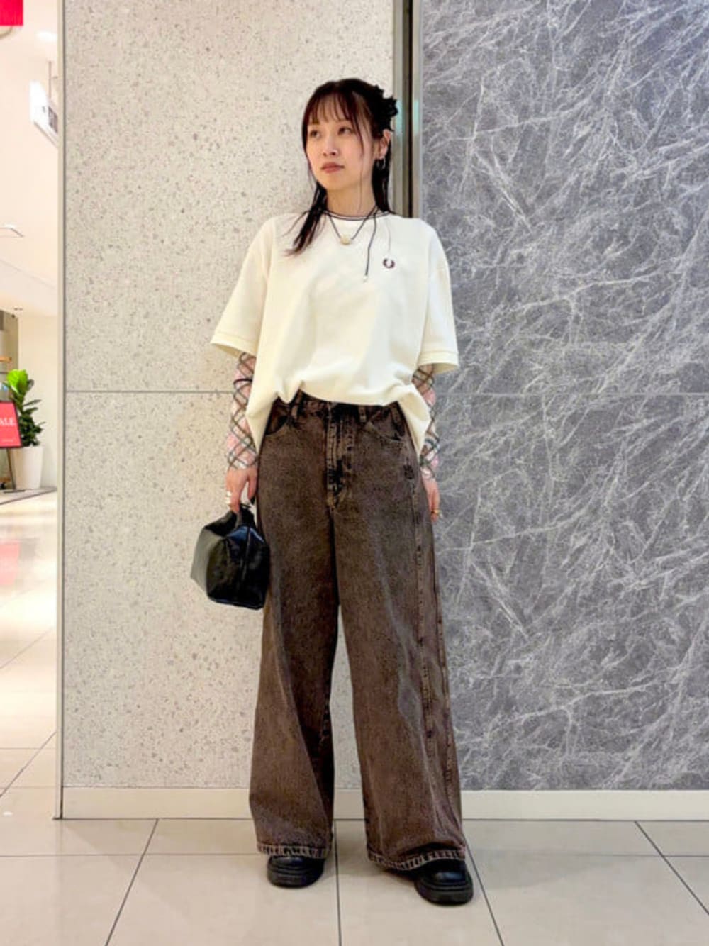 ブラウン系のデニムパンツ、ブラック系のショルダーバッグ、ベージュ系のTシャツ/カットソーを着用したレディースの夏コーディネートの1枚目の写真