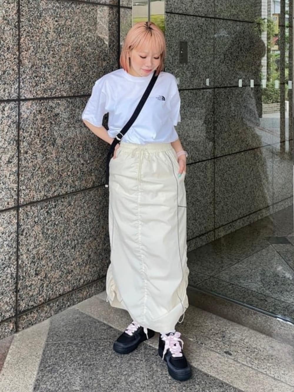 ホワイト系のスカート、ブラック系のトートバッグ、ブラック系のスニーカーを着用したレディースの春コーディネートの1枚目の写真