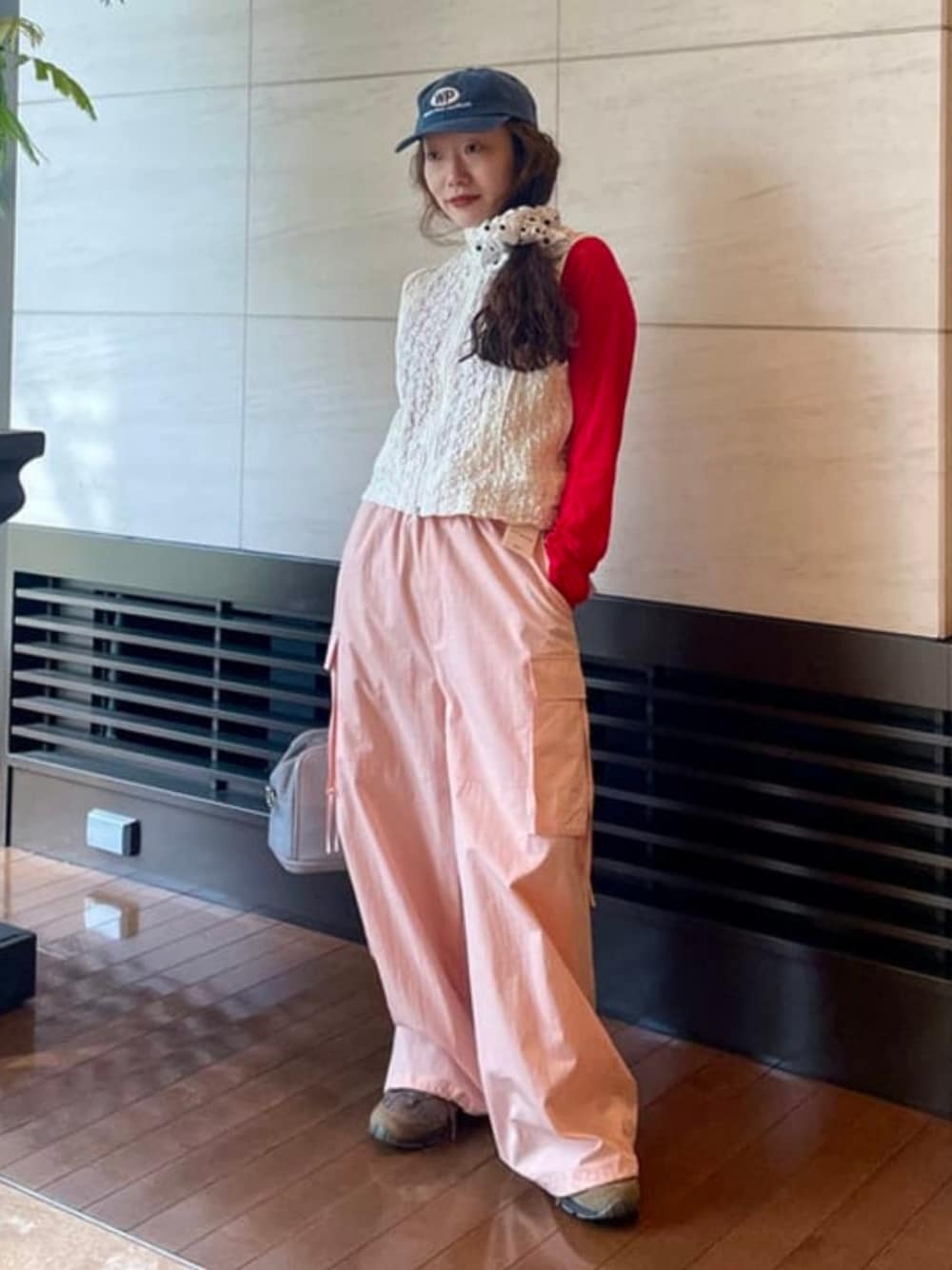 レッド系のカーディガン/ボレロ、ピンク系のカーゴパンツ、ホワイト系のベストを着用したレディースの春コーディネートの1枚目の写真