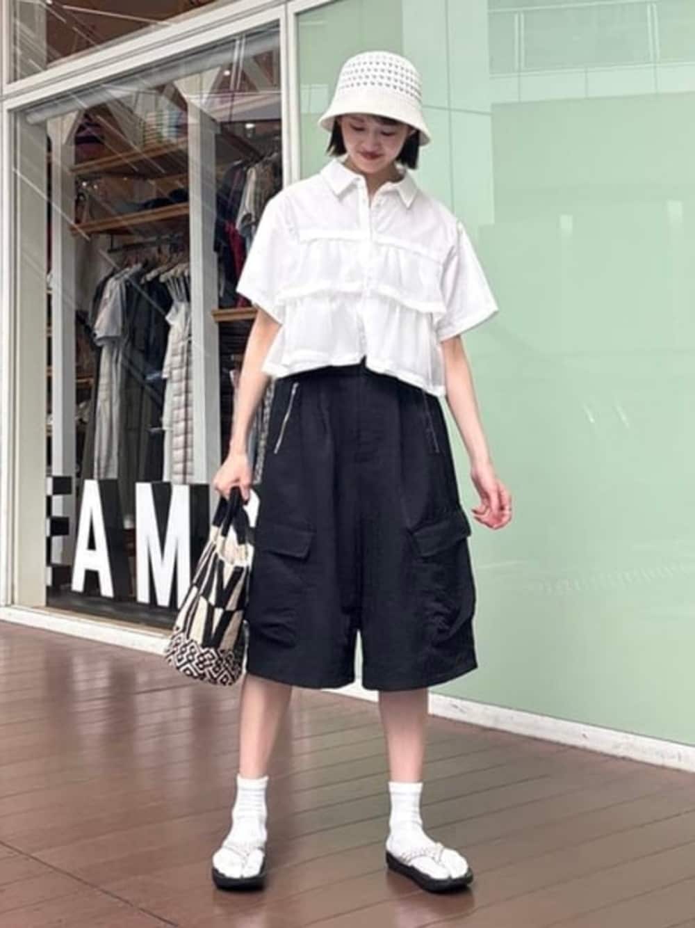 ブラック系のトートバッグ、ブラック系のカーゴパンツ、ホワイト系のシャツ/ブラウスを着用したレディースの夏コーディネートの1枚目の写真