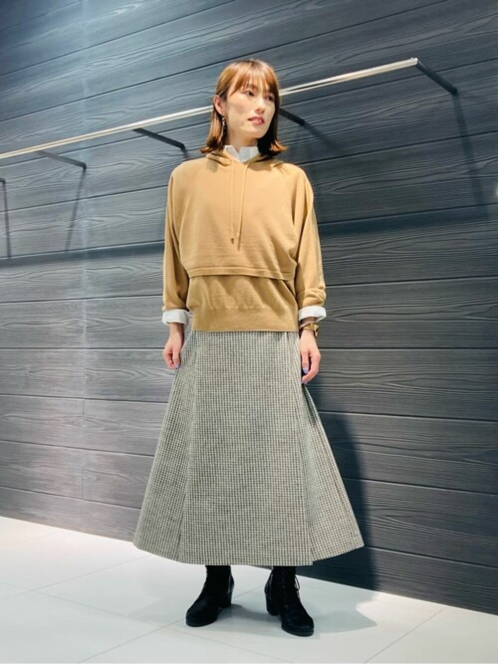 イエロー系のアンサンブル、ホワイト系のシャツ/ブラウス、ブラウン系のスカートを着用したレディースの冬コーディネートの1枚目の写真