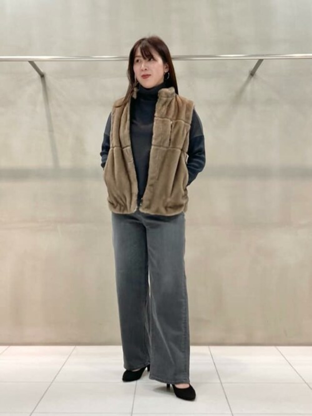 ブラウン系のベスト、ブラック系のTシャツ/カットソー、グレー系のデニムパンツを着用したレディースの冬コーディネートの1枚目の写真