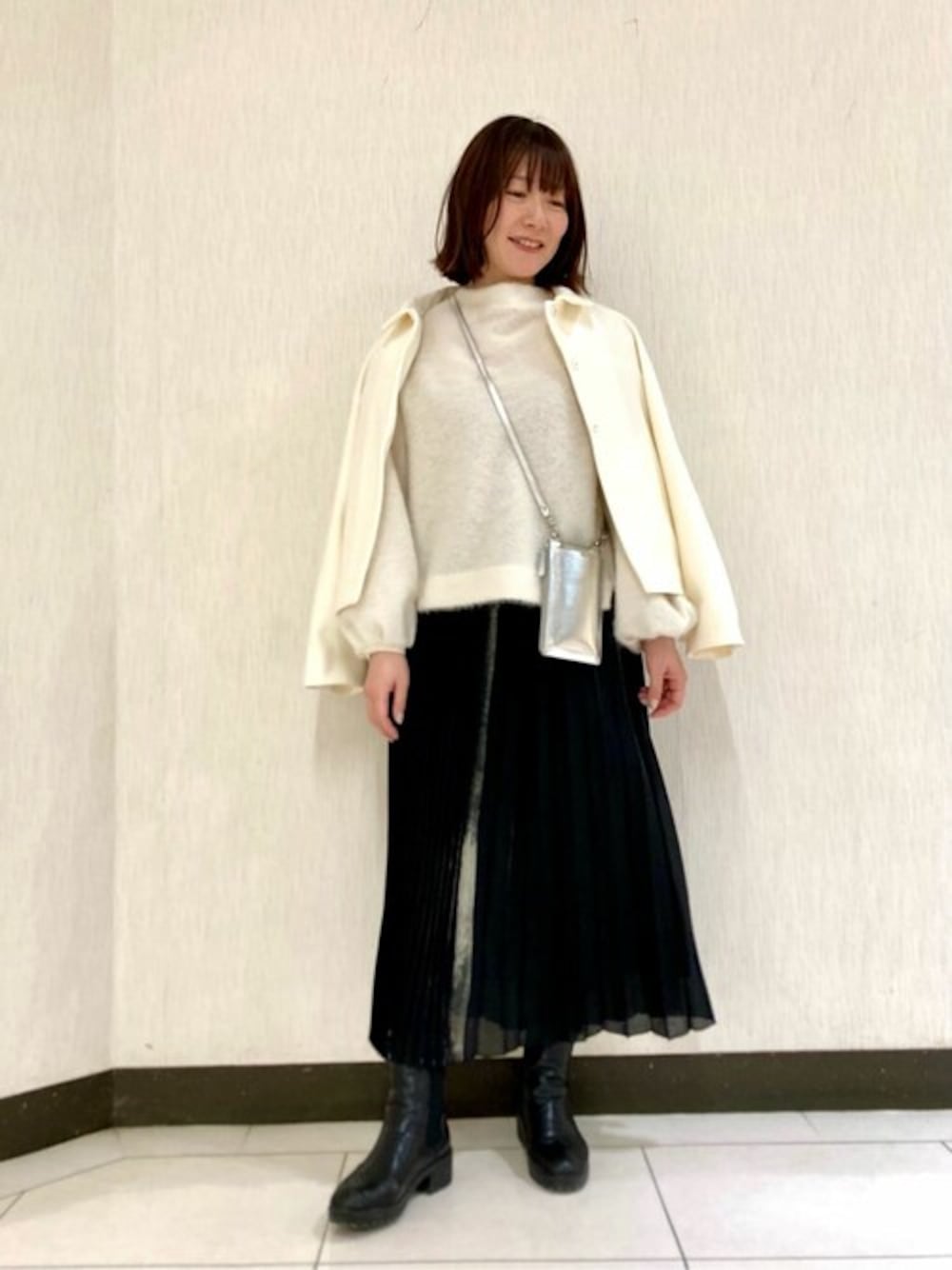 ホワイト系のその他アウター、ホワイト系のTシャツ/カットソー、ブラック系のスカートを着用したレディースの冬コーディネートの1枚目の写真