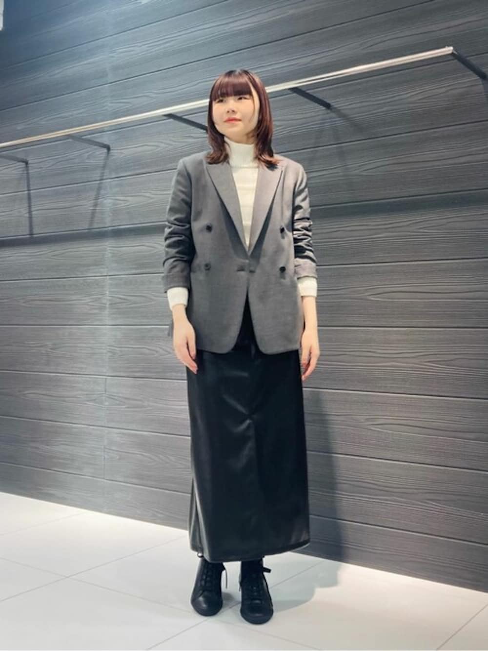 グレー系のスーツジャケット、ホワイト系のニット/セーター、ブラック系のスカートを着用したレディースの冬コーディネートの1枚目の写真