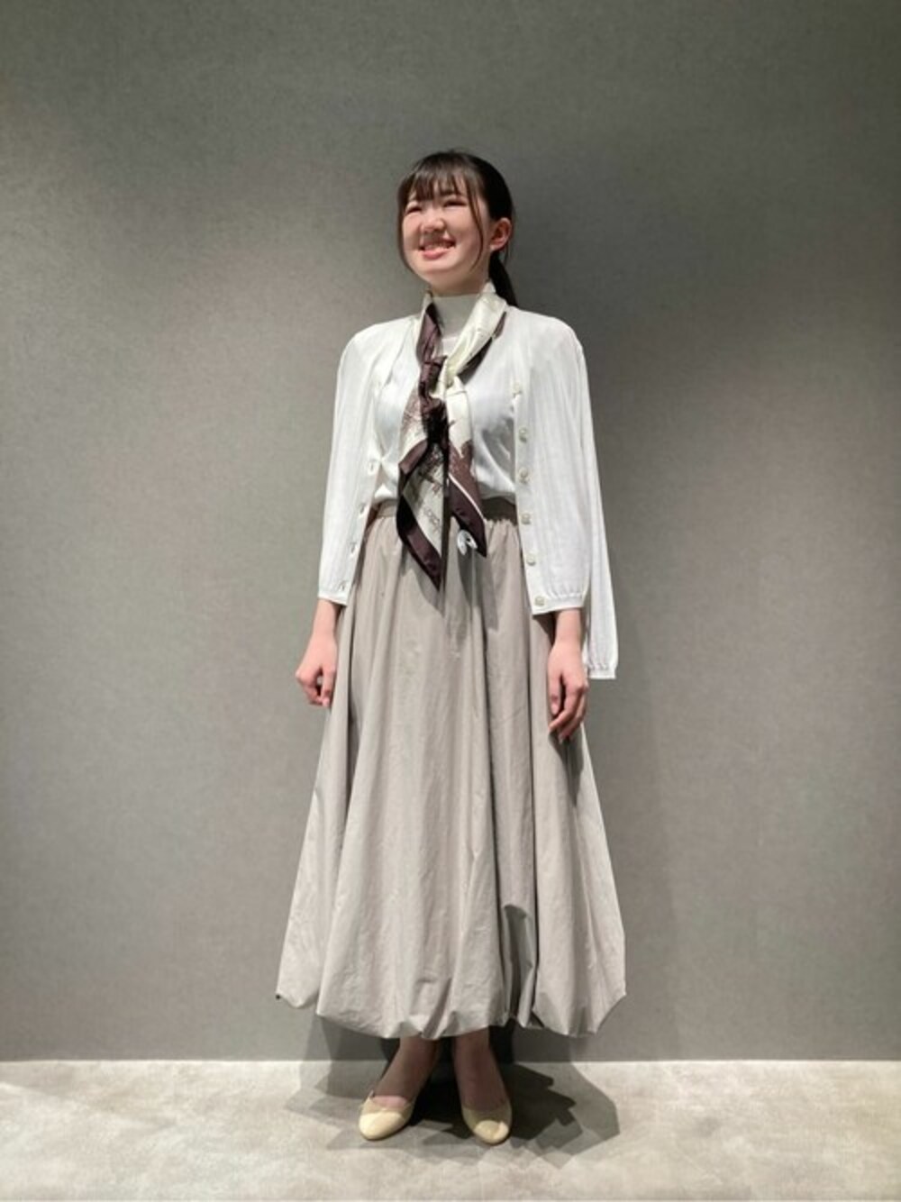 ホワイト系のカーディガン/ボレロ、ホワイト系のニット/セーター、ベージュ系のスカートを着用したレディースの春コーディネートの1枚目の写真