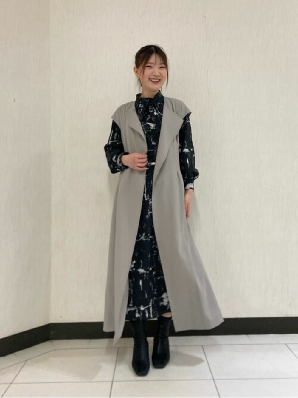 ブラック系のワンピース、ベージュ系のトレンチコート、ブラック系のベルトを着用したレディースの春コーディネートの1枚目の写真