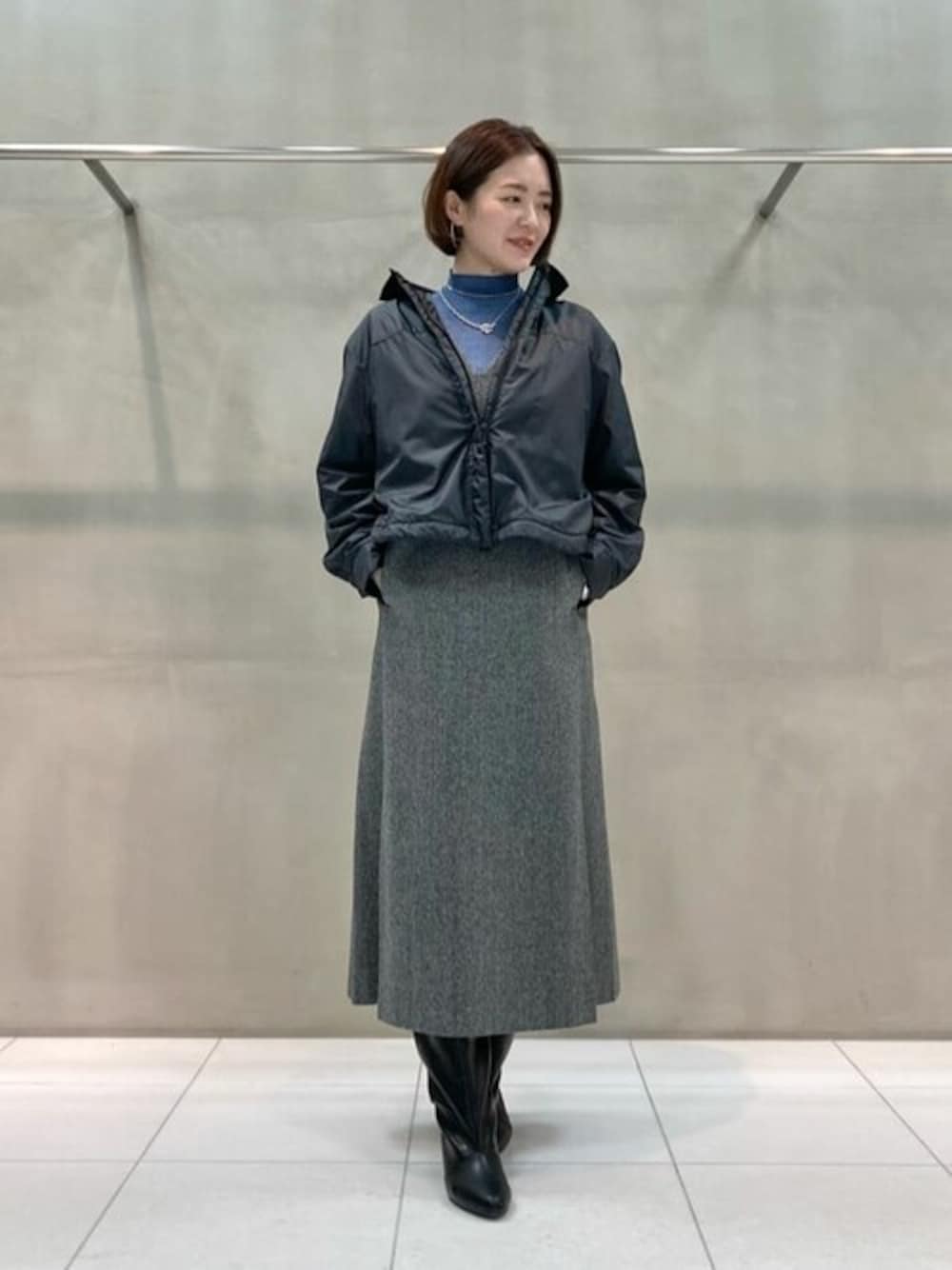 ブラック系のブルゾン、ブルー系のニット/セーター、グレー系のワンピースを着用したレディースの春コーディネートの1枚目の写真