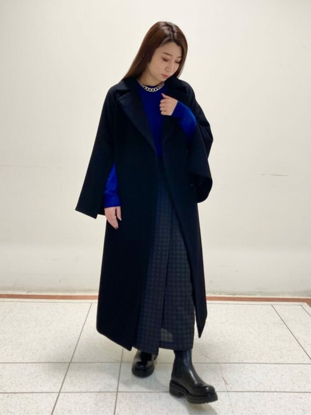 ブルー系のニット/セーター、ブラック系のスカートを着用したレディースの春コーディネートの1枚目の写真
