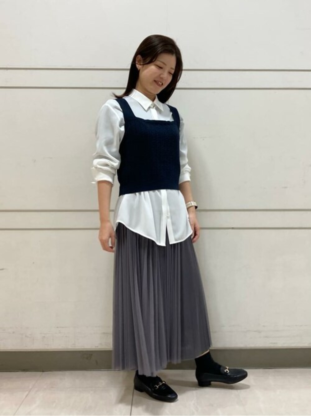 ブルー系のニット/セーター、ホワイト系のシャツ/ブラウス、グレー系のスカートを着用したレディースの春コーディネートの1枚目の写真