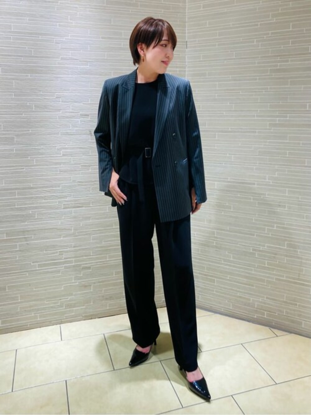 グレー系のセットアップ、ブラック系のシャツ/ブラウス、ブラック系のスラックスを着用したレディースの春コーディネートの1枚目の写真