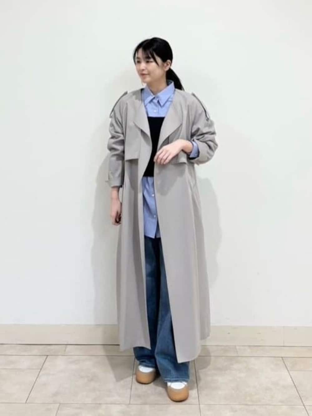 ベージュ系のトレンチコート、ブルー系のニット/セーター、ブルー系のシャツ/ブラウスを着用したレディースの春コーディネートの1枚目の写真