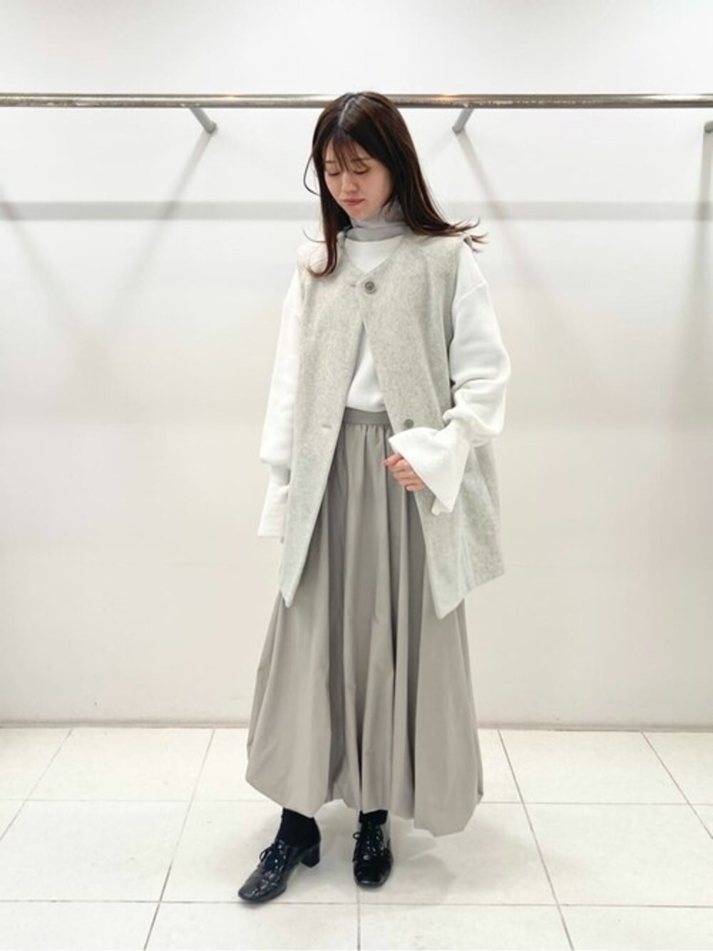 グレー系のベスト、ホワイト系のニット/セーター、グレー系のTシャツ/カットソーを着用したレディースの春コーディネートの1枚目の写真